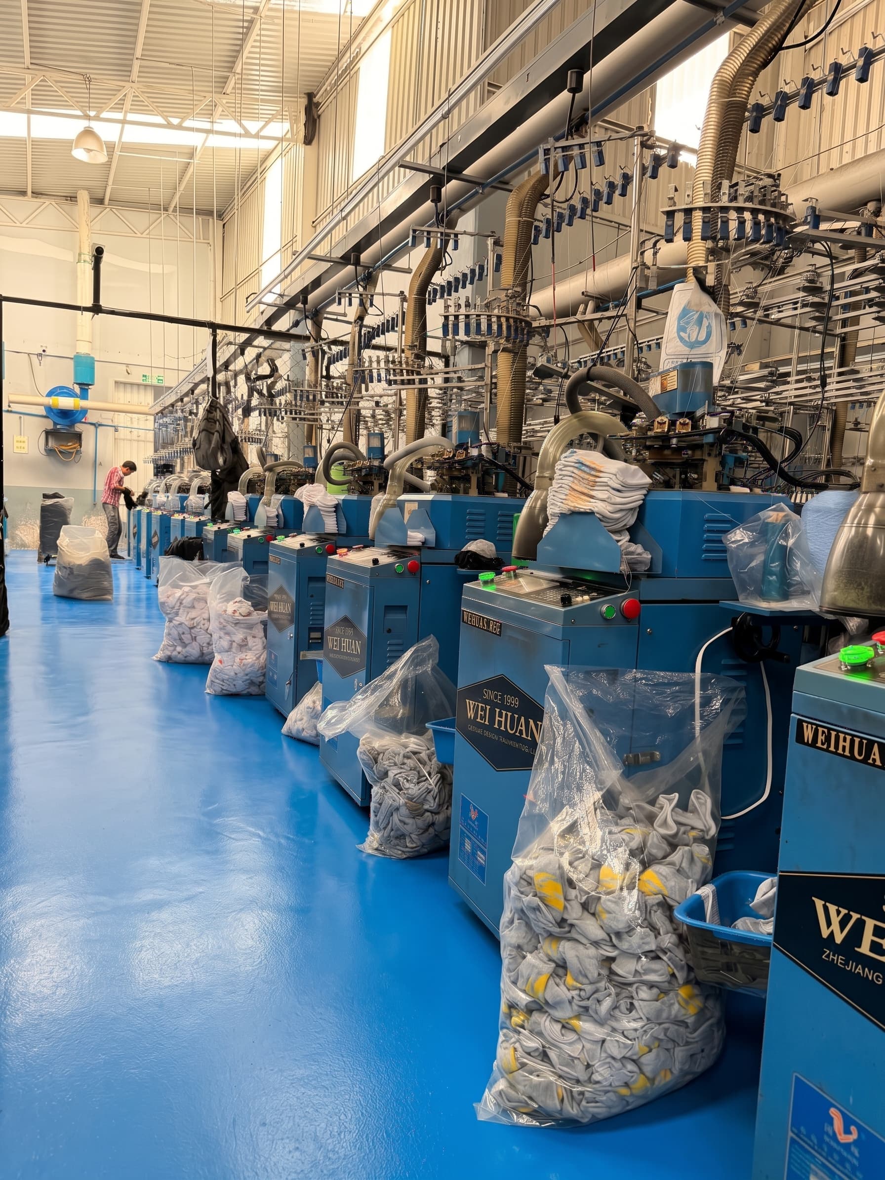 Hilera de máquinas circulares tejiendo calcetas y calcetines en la fábrica Francés